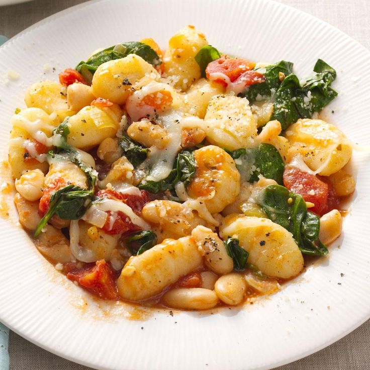 a white plate topped with pasta and spinach