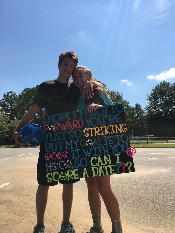 two people standing next to each other holding a sign