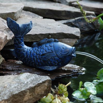 a blue fish statue sitting on top of some rocks