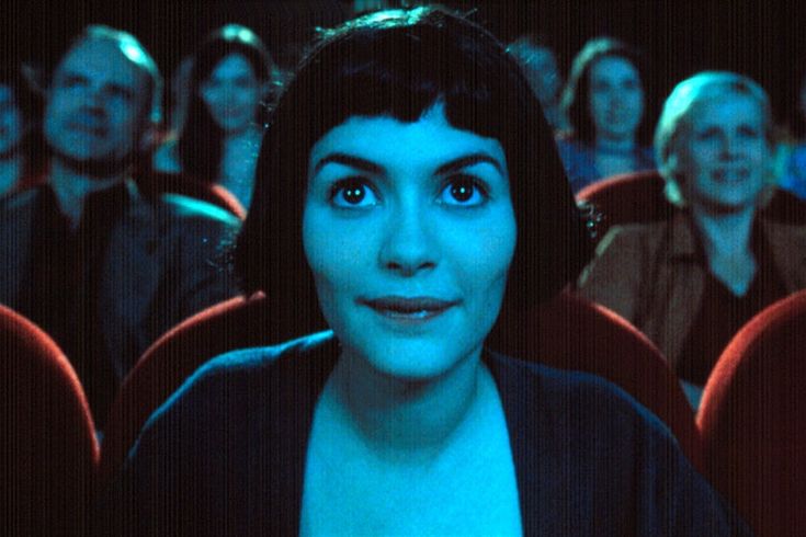 a woman with dark hair and blue eyes sitting in front of an audience