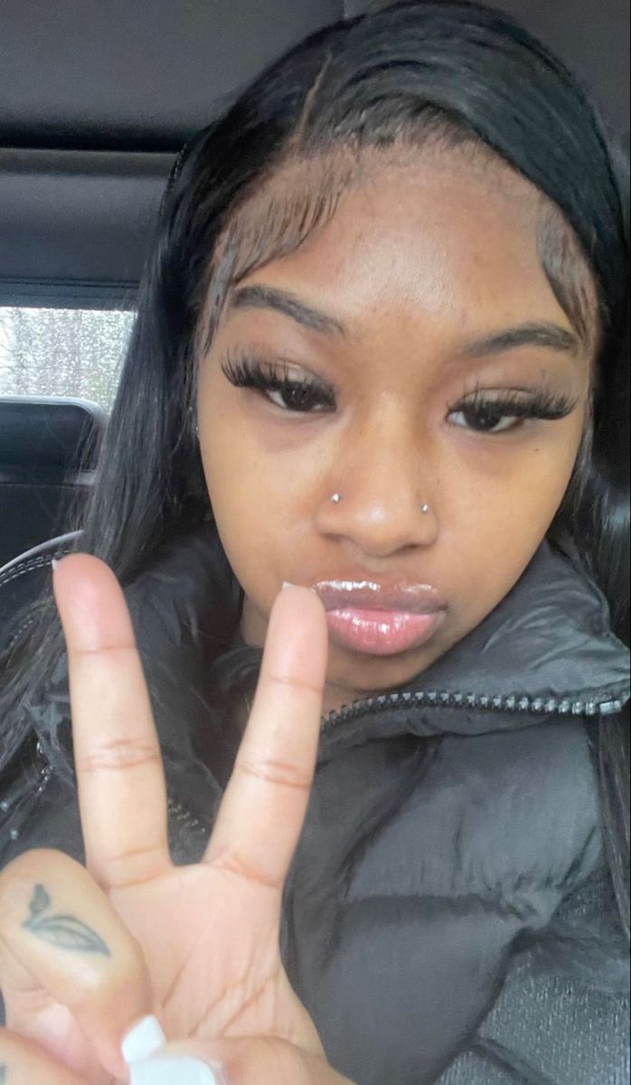 a woman making the peace sign with her hand in front of her face while sitting in a car