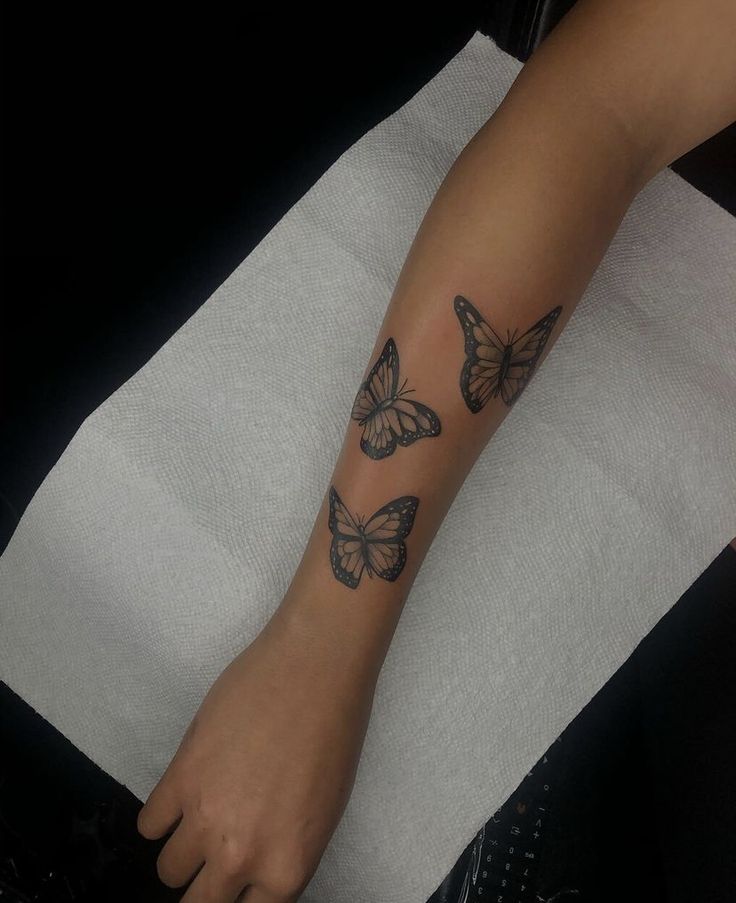 a woman's foot with three butterflies tattooed on her left arm and the other leg