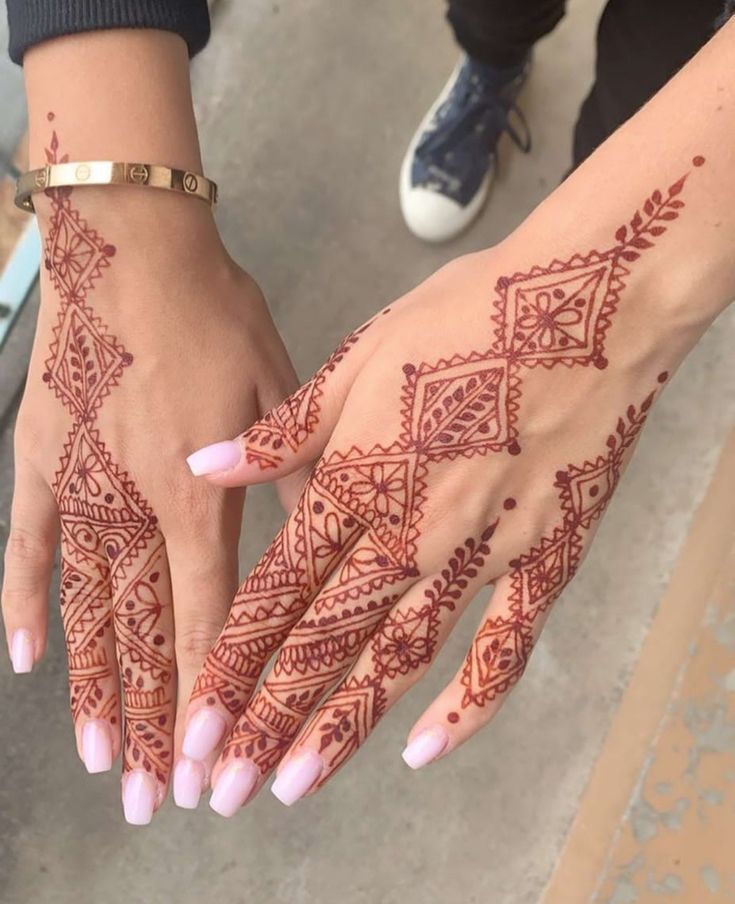 two hands with henna designs on them and one is holding the other's hand