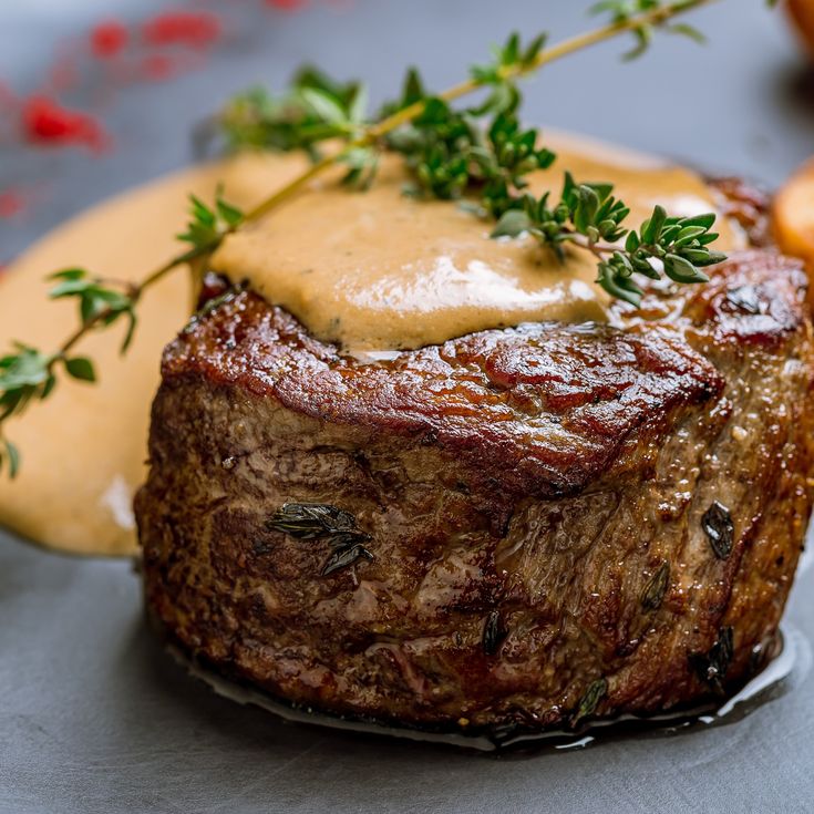 a steak covered in gravy and garnished with parsley