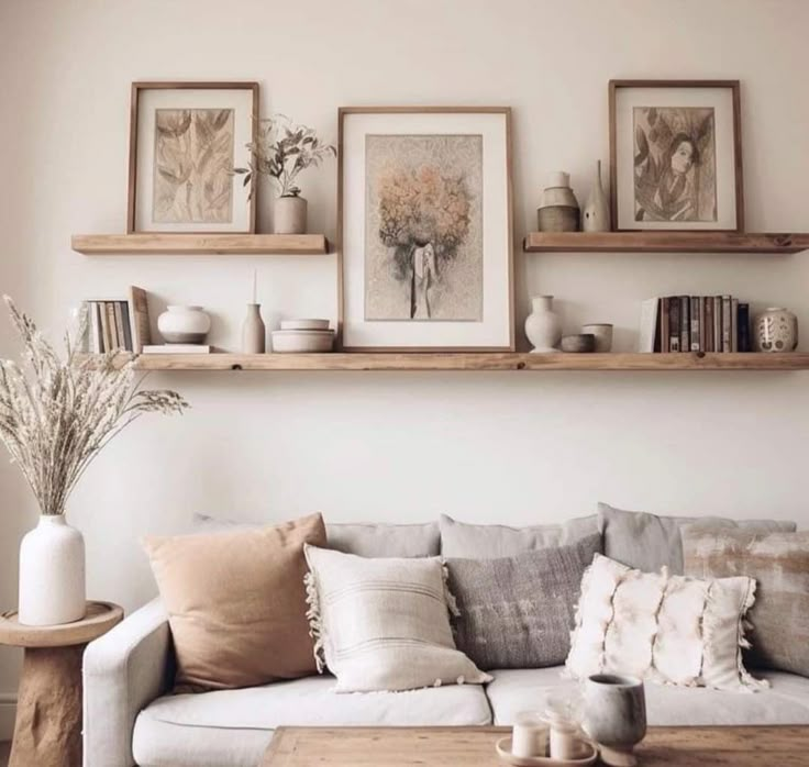 a living room filled with lots of furniture and shelves above the couch, along with pictures on the wall