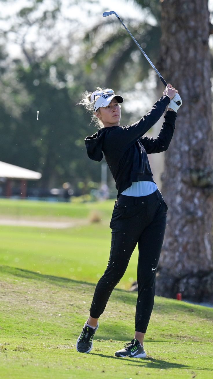 a woman is swinging her golf club on the course