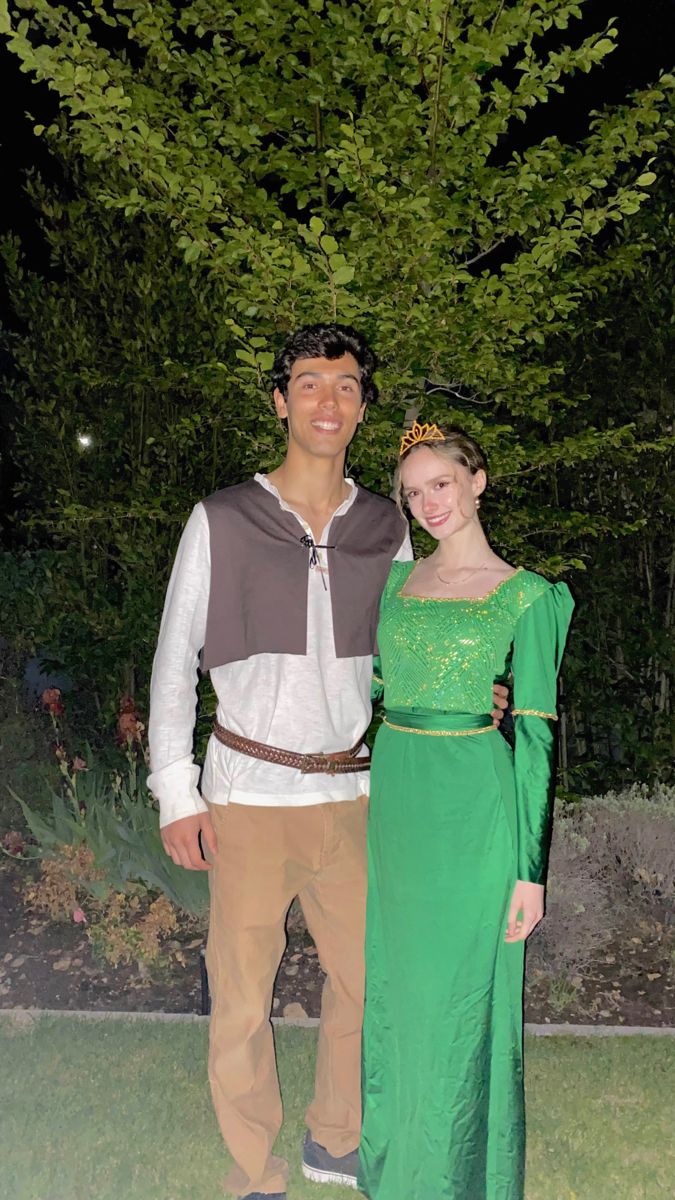 a man and woman standing next to each other in front of a tree at night