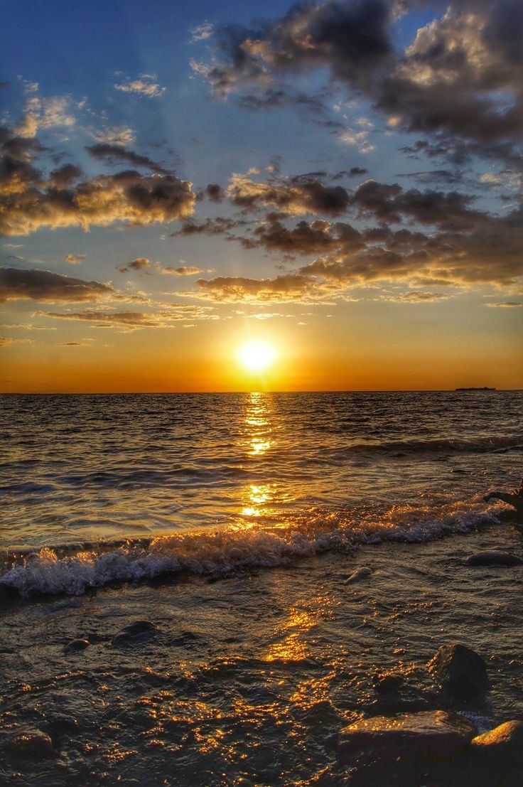 the sun is setting over the ocean with waves