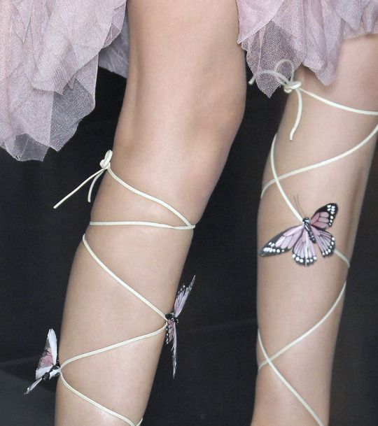 the legs and ankles of a woman with butterfly tattoos on their feet, tied together