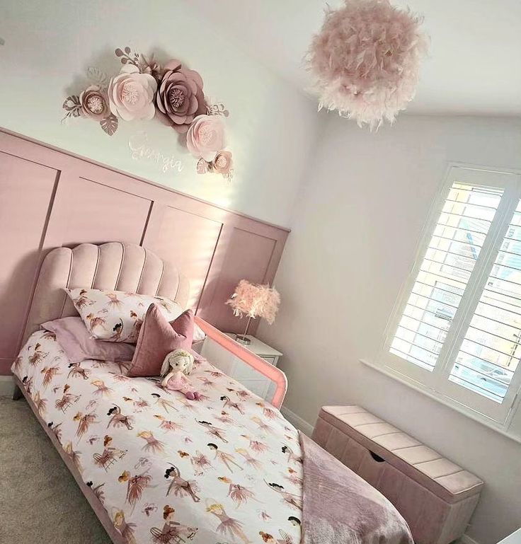 a bedroom decorated in pink and white with flowers on the wall