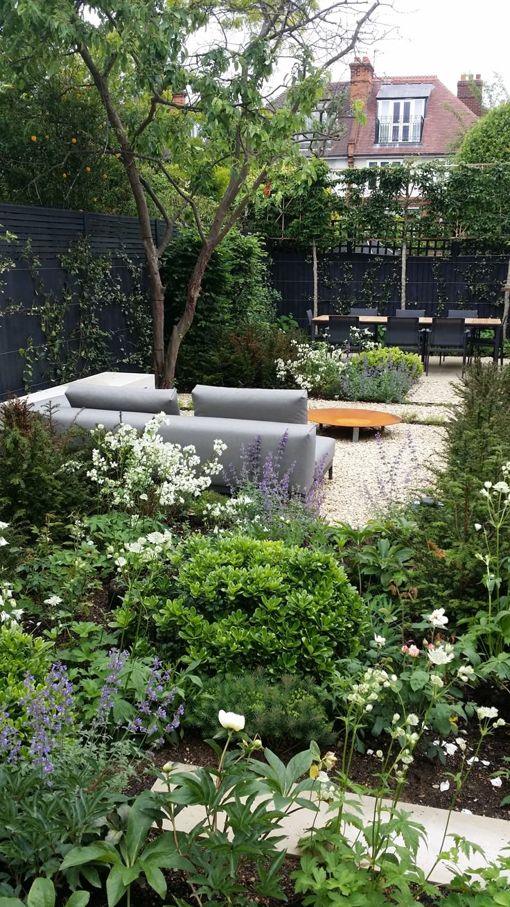 an outdoor seating area surrounded by plants and flowers in the foreground is a bench