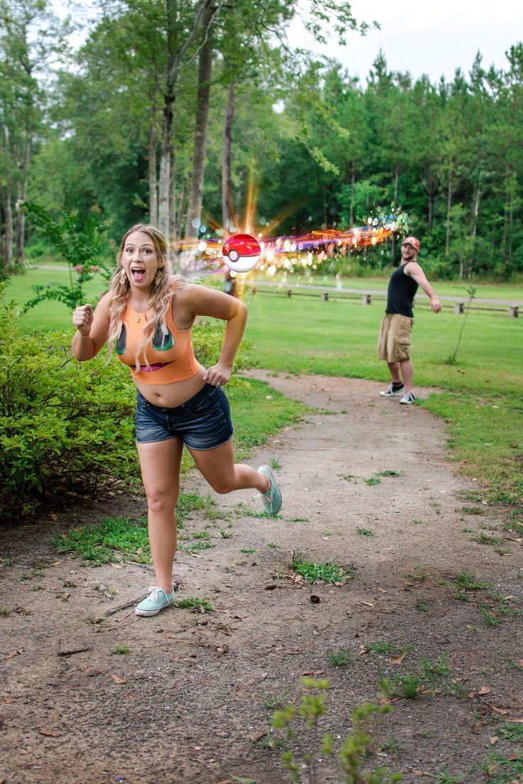 a woman running down a dirt road next to a forest