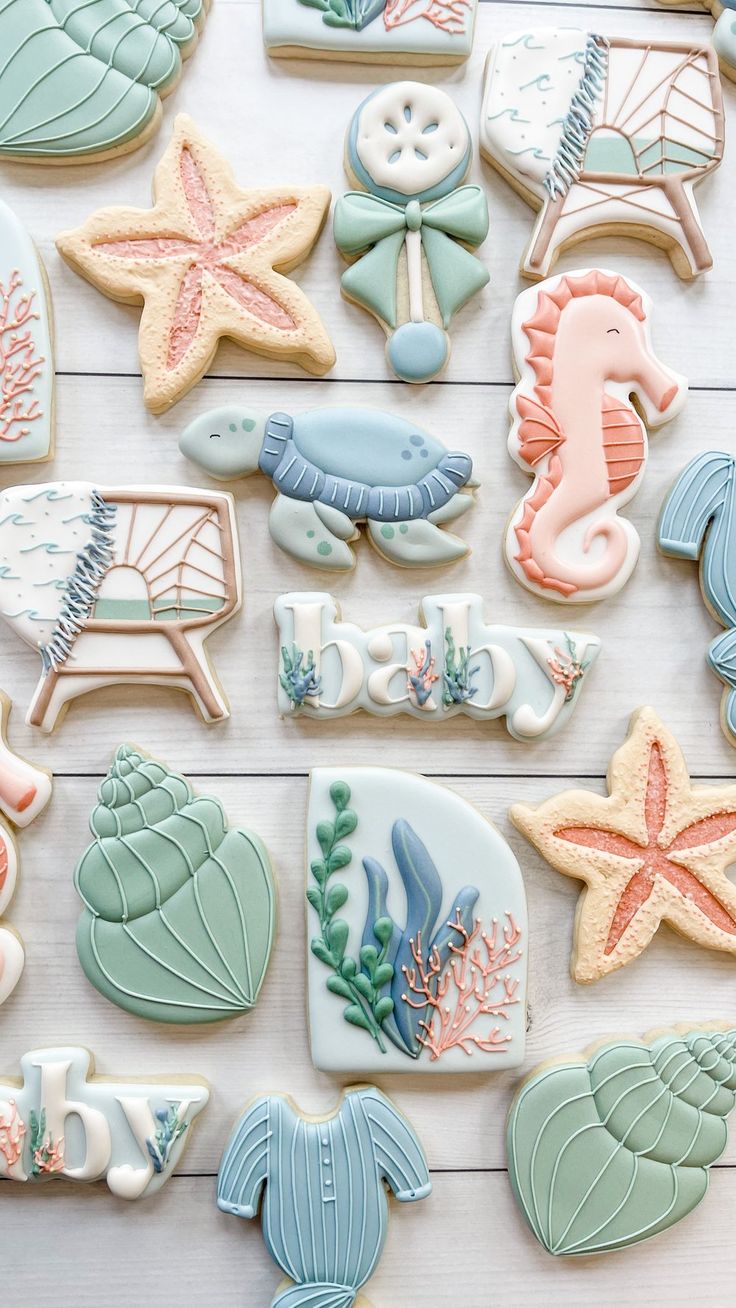 decorated cookies with sea animals and seashells are arranged on a white wooden surface