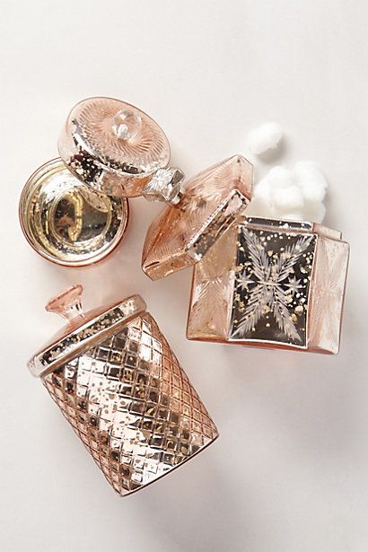 three pieces of jewelry sitting on top of a white table next to a bottle of perfume