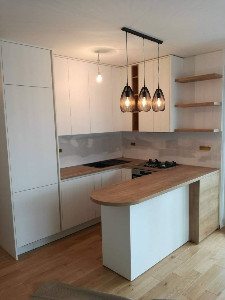 a kitchen with white cabinets and wooden counter tops next to a stove top oven under three hanging lights