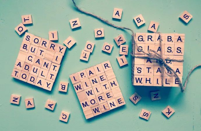 several scrabble tiles tied with twine and string on turquoise background, including letters that spell out words