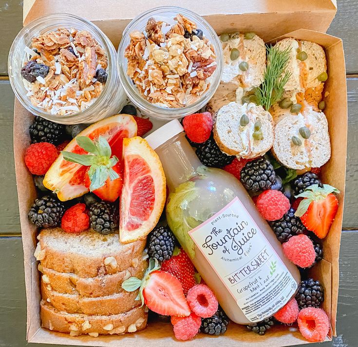 an open box filled with fruit, nuts and yogurt on top of a wooden table