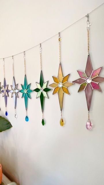 a bunch of different colored stars hanging from a line next to a potted plant