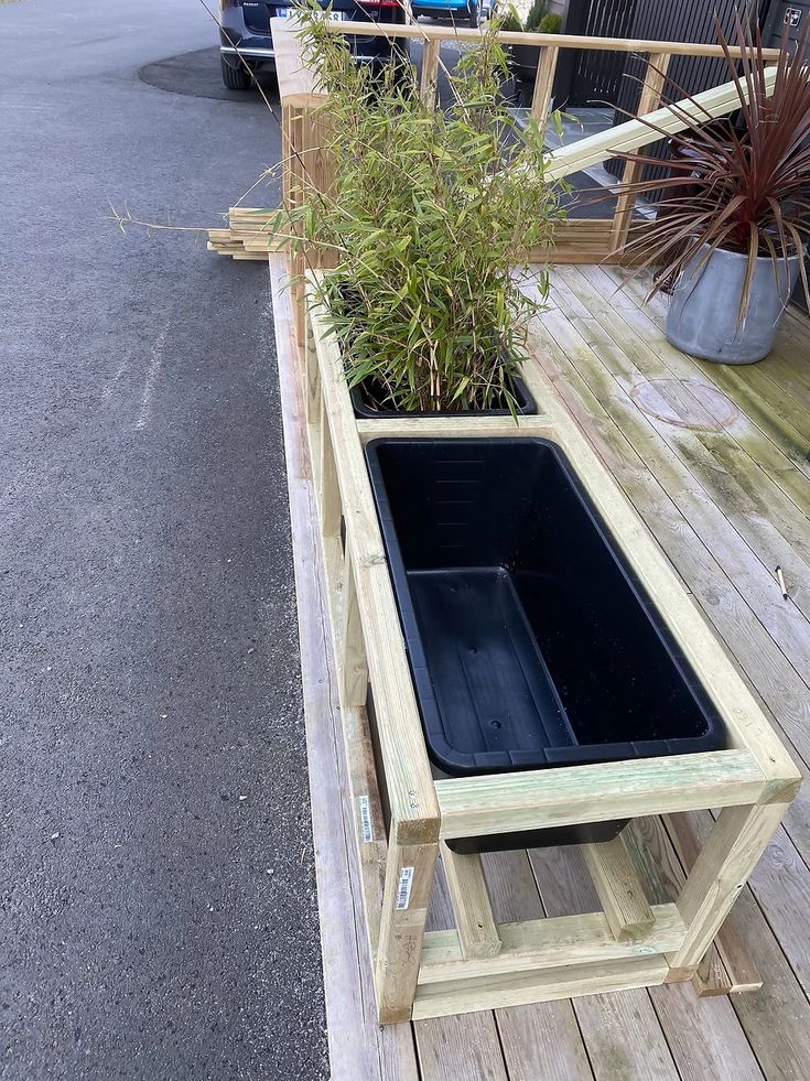 a wooden planter filled with plants on top of a wooden floor next to a parking lot