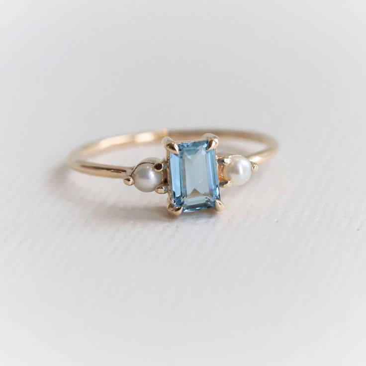 an aqua and white topazte ring with pearls on the sides, set in gold