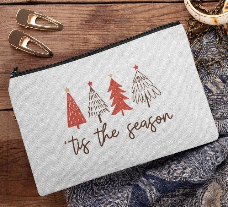 a white zippered pouch with red trees on it and the words tis the season