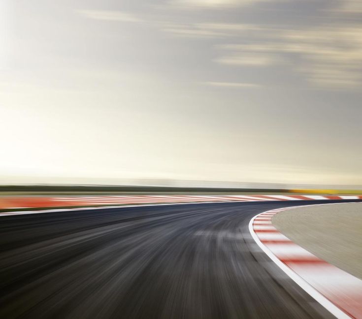 a car driving on a race track with motion blurry image in the foreground