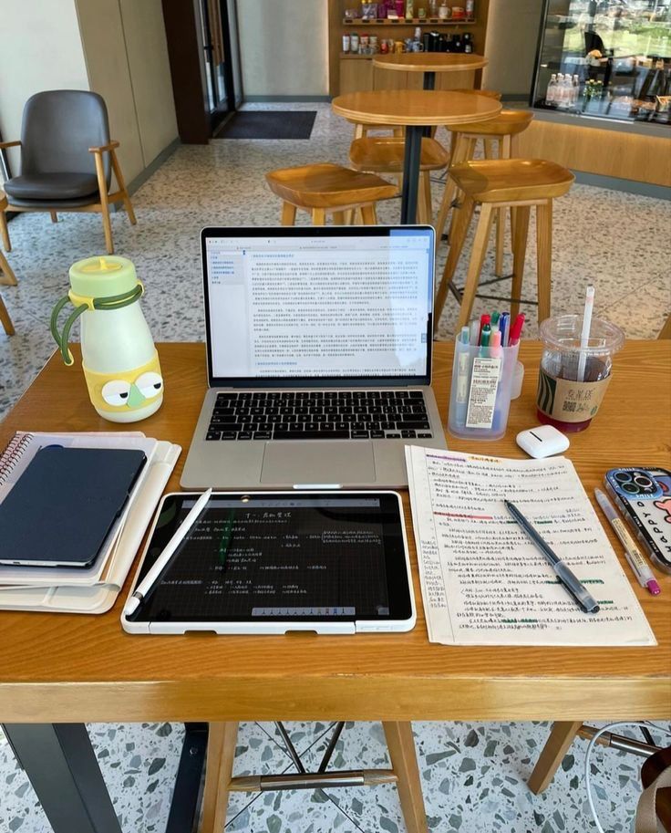 an open laptop computer sitting on top of a wooden desk next to a notebook and pen