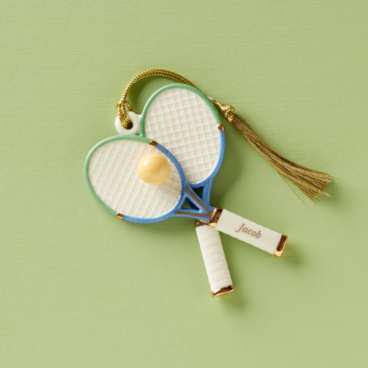 two tennis racquets are hanging on a keychain that is shaped like a heart