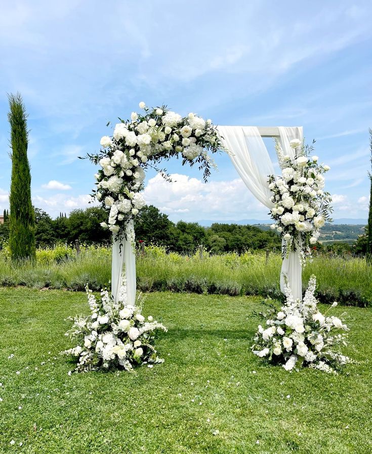 an outdoor ceremony setup with white flowers and greenery