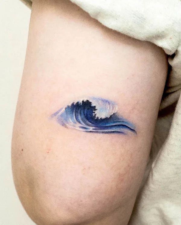 a woman's thigh with a blue wave tattoo on her left side ribcage