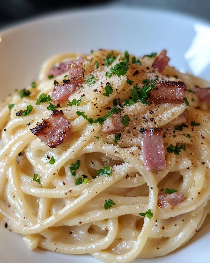 pasta with bacon and parmesan cheese in a white bowl on a table top