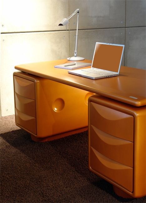 an orange desk with a laptop on it and a lamp in the corner next to it