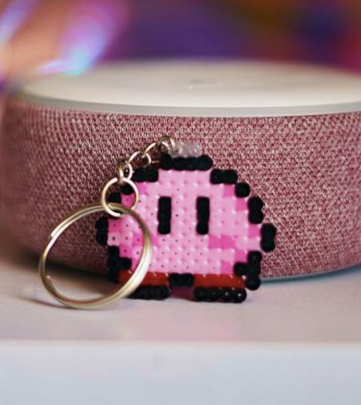 a pink pacman keychain is sitting on a table