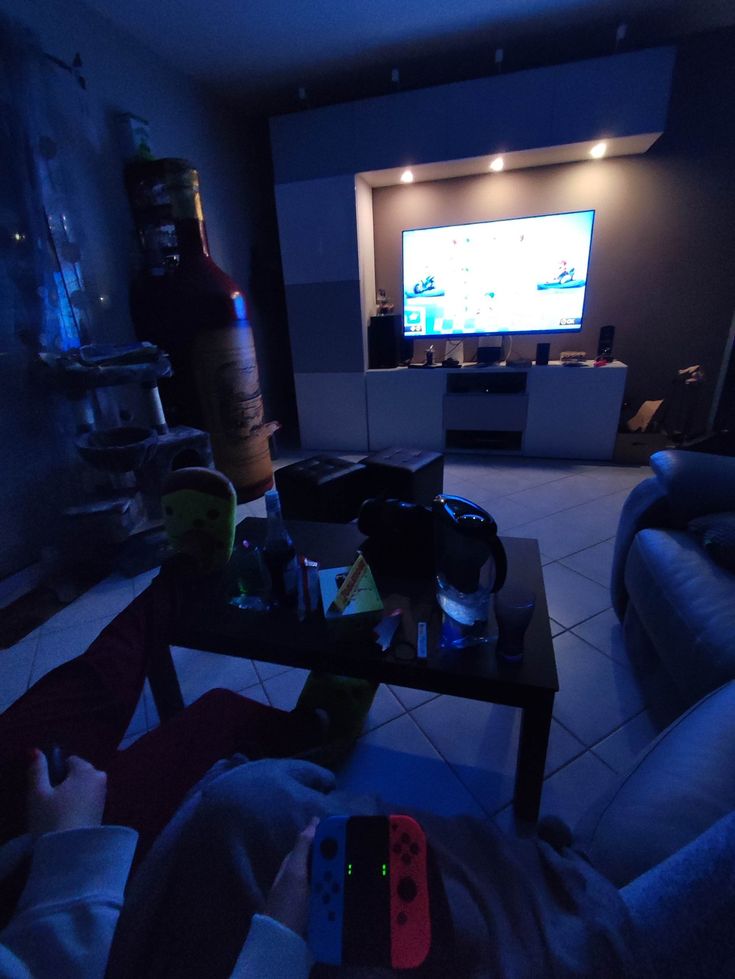 a man laying on the floor in front of a tv playing video games at night