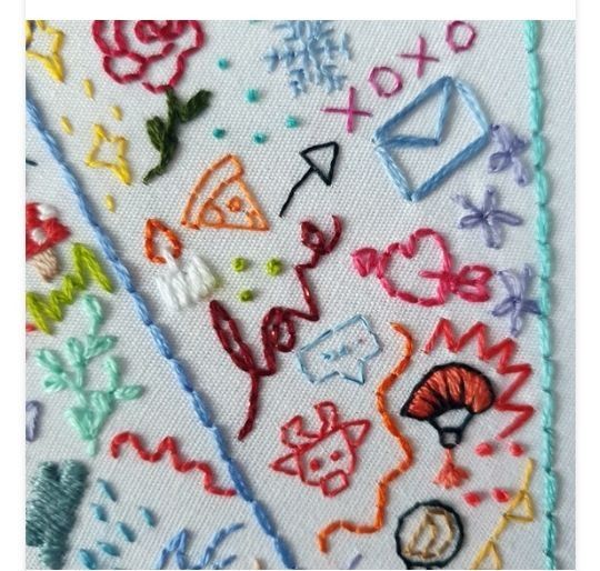 a close up of a piece of cloth with various embroidered designs on it, including letters and numbers