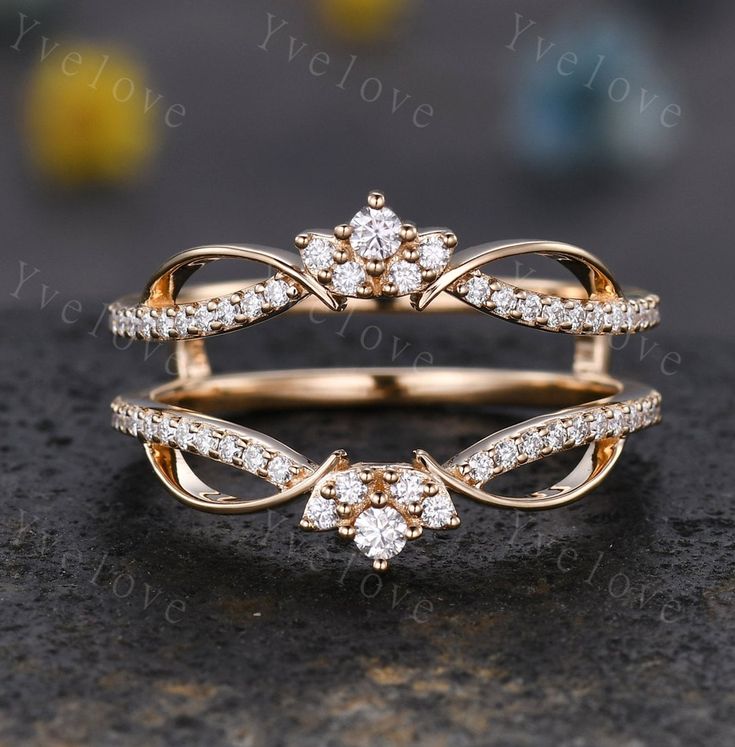 two gold rings with white diamonds on top and bottom, sitting on a black surface