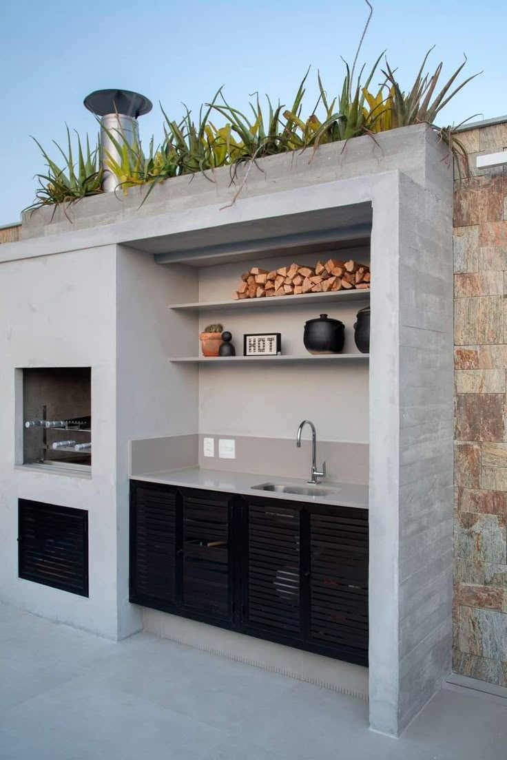 an outdoor kitchen is built into the side of a building with plants growing on top