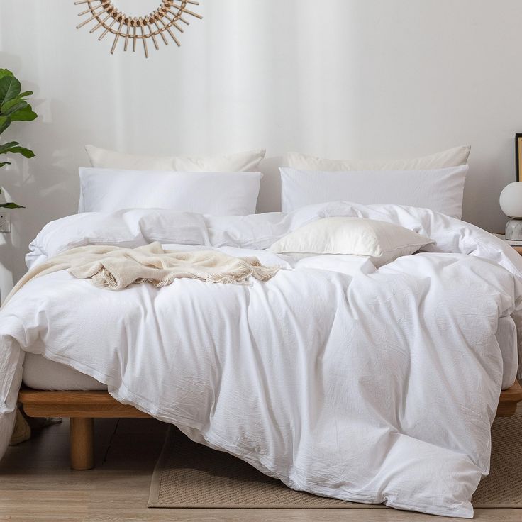 an unmade bed with white sheets and pillows on top of it in a bedroom