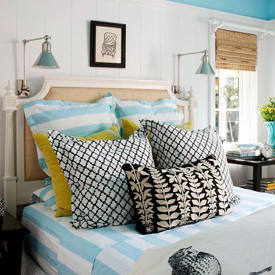 a bed with blue and white sheets, pillows and pictures on the wall above it