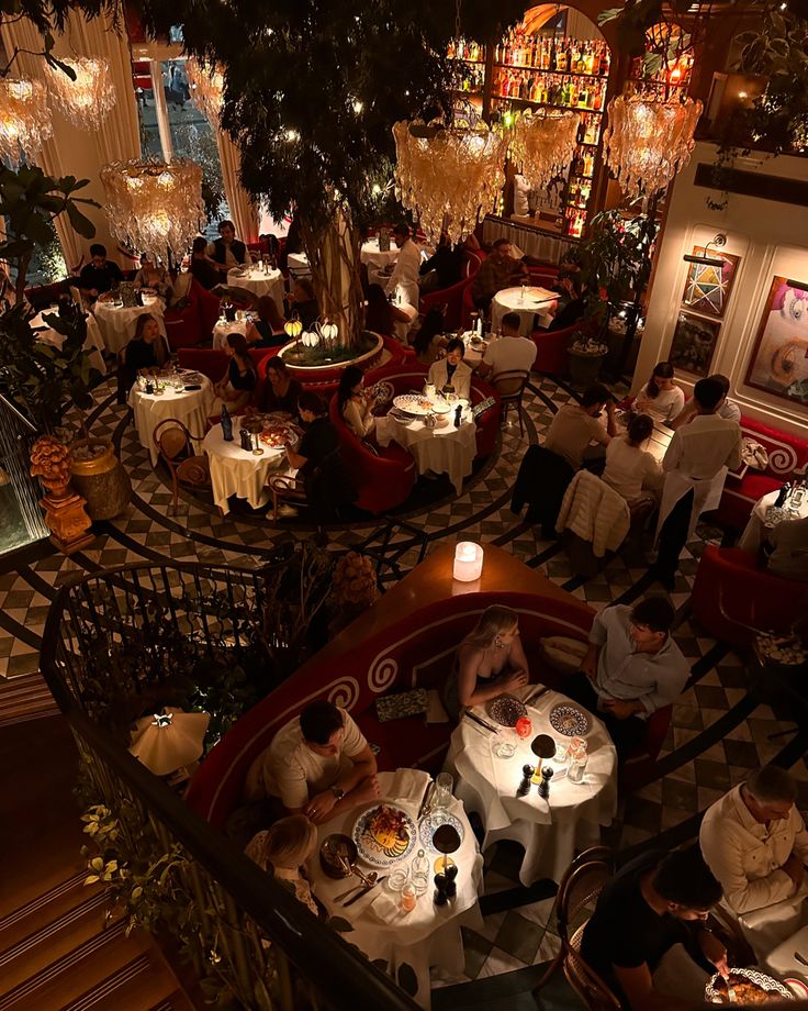 people sitting at tables in a restaurant with chandeliers