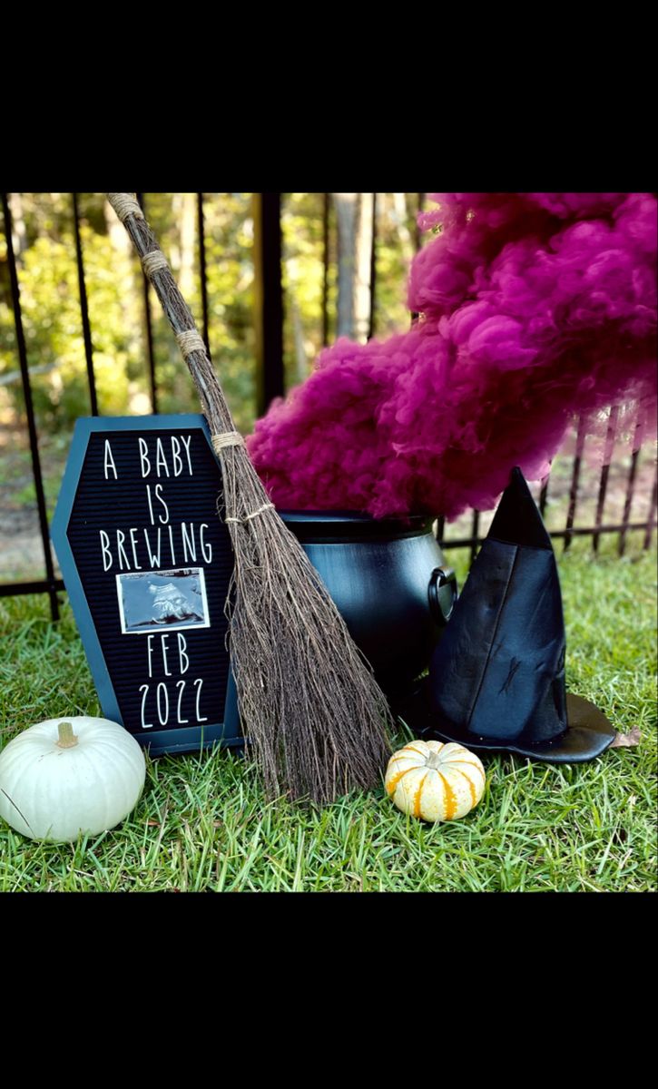 a witch's hat, broom and other items on the grass near a sign that says baby is brewing