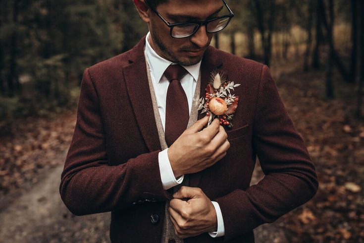 a man in a suit and tie is looking down at his boutonniere