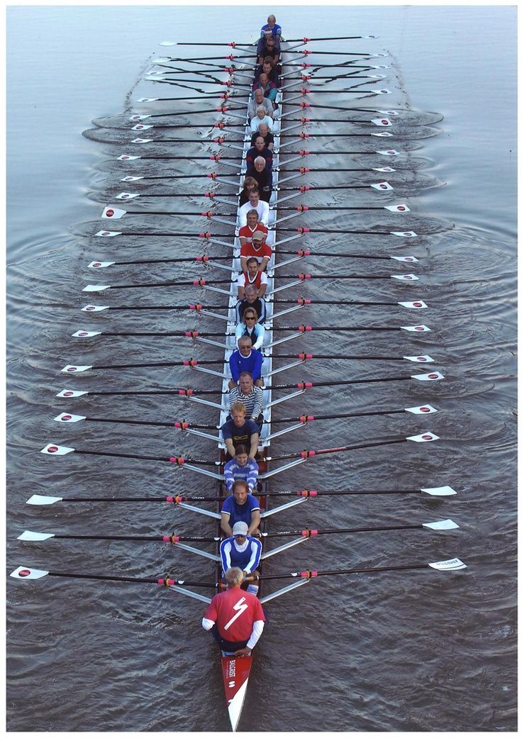 several people are rowing in a boat on the water with their backs to each other