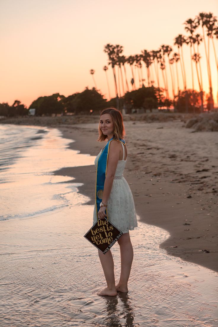 a woman is standing in the water at the beach with her hand on her hip