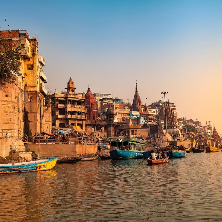 several boats floating on the water in front of old buildings and tall spires at sunset