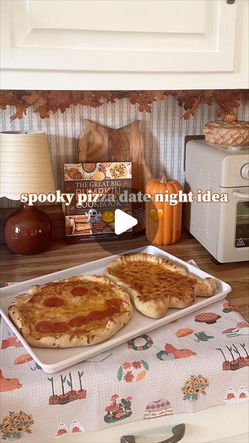 two pizzas sitting on top of pans in front of a toaster oven