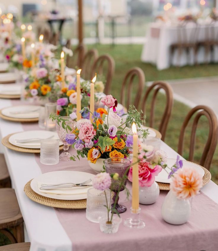 a long table is set with flowers and candles for an outdoor dinner party or gathering