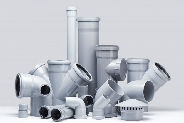 an assortment of white plastic pipes and fittings on a gray background with room for text