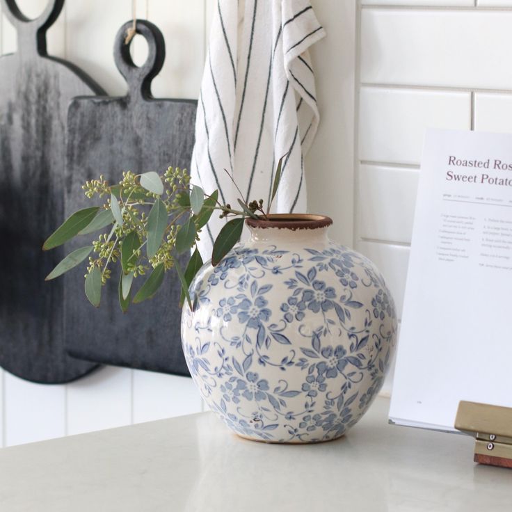 a blue and white vase sitting on top of a counter next to a book shelf