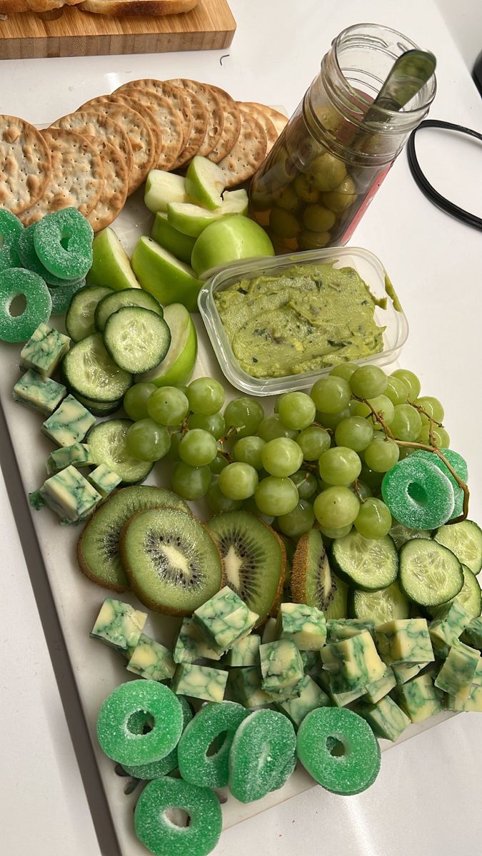 grapes, cucumbers, kiwis and crackers on a cutting board